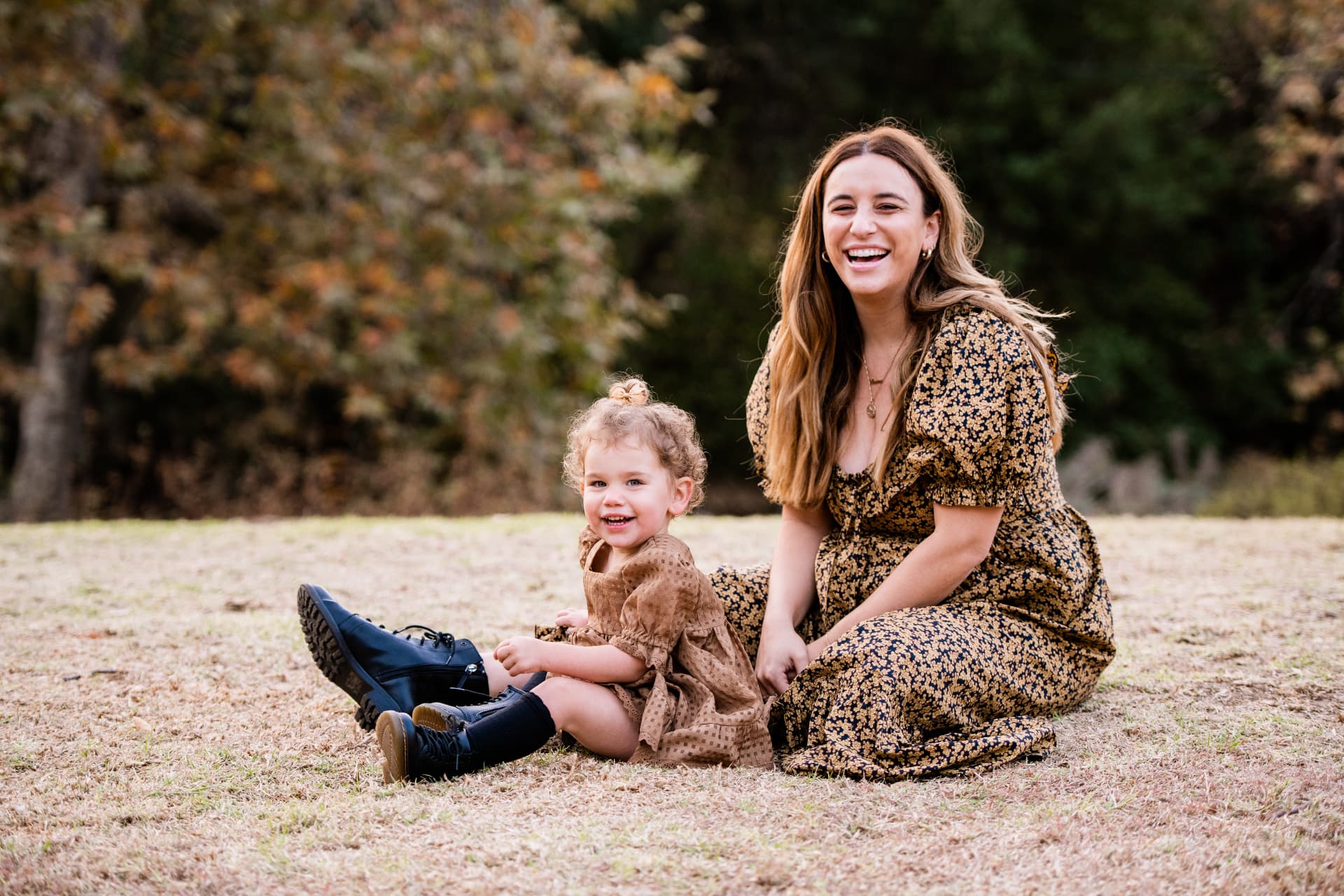 Mother and daughter sitting in a golden autumn field in coordinated prints