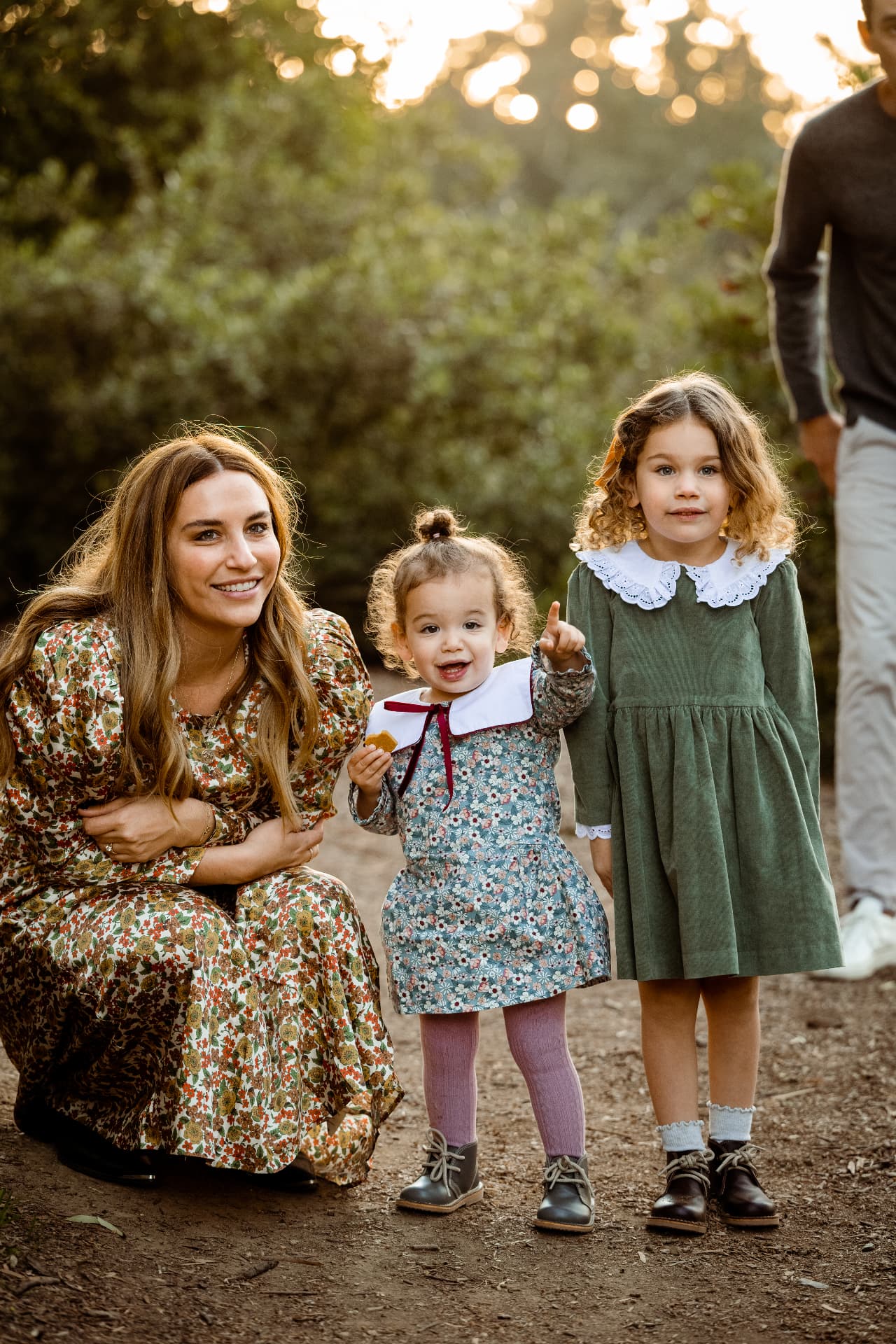 Mother in a floral dress with her two daughters in green and blue prints on a sunset trail